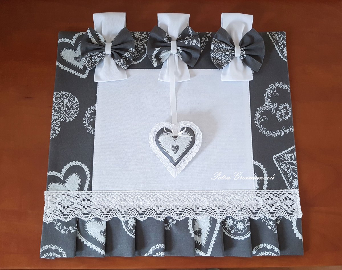 Závěs na troubu v šedém provedení s motivem bílých srdíček, lemovaný bílou krajkou šíře 45 mm