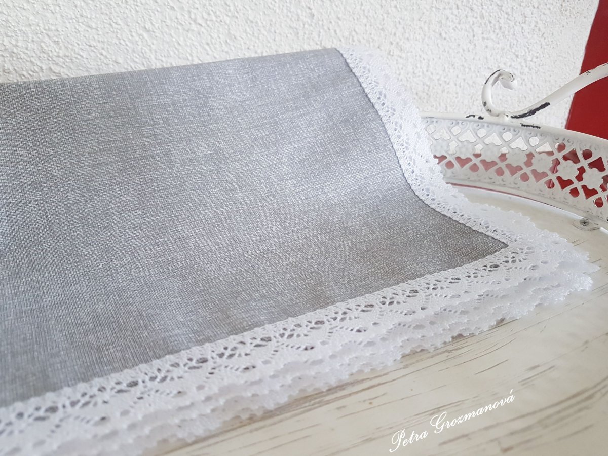 Dekorační prostírání ve světle šedém provedení, lemované bílou krajkou šíře 25 mm