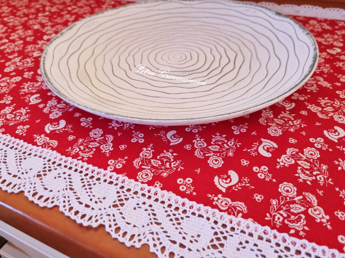 Běhoun v červeném provedení s motivem folkloru, lemovaný bílou krajkou šíře 45 mm