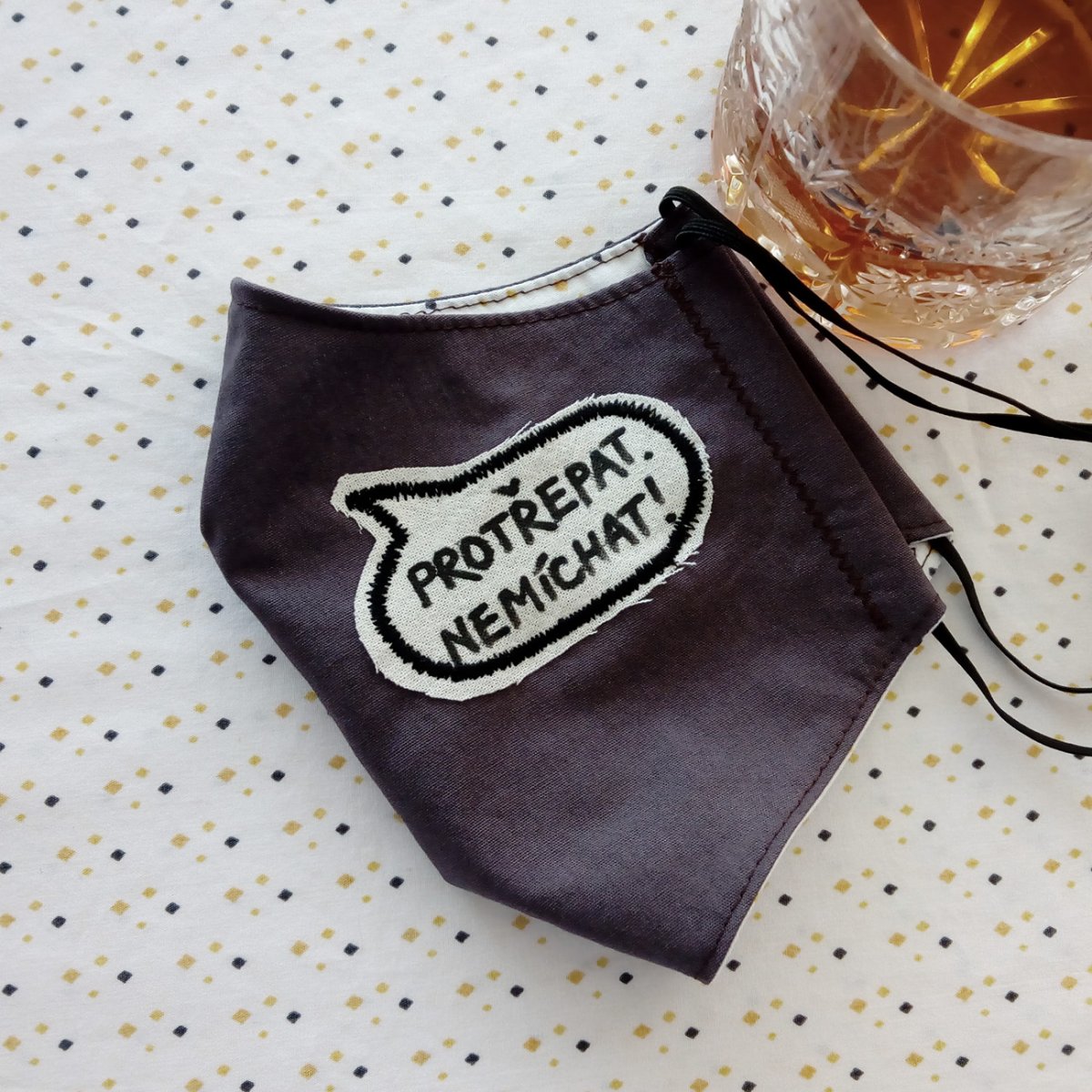 Šedá rouška s nápisem Protřepat, nemíchat!