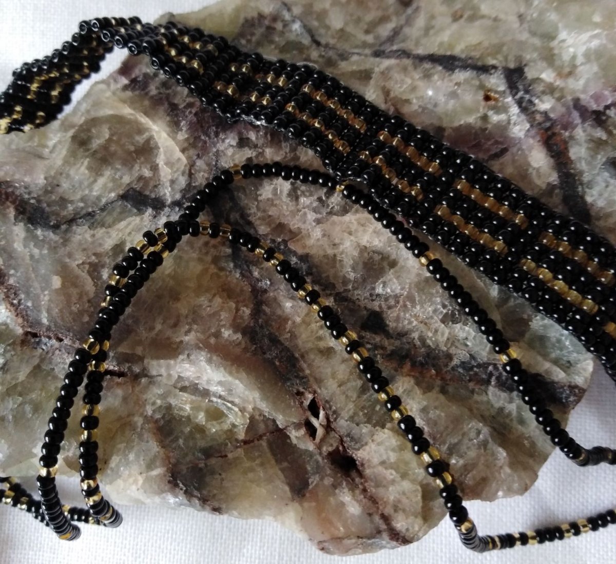 Náramek na nohu z černých a zlatých korálků 