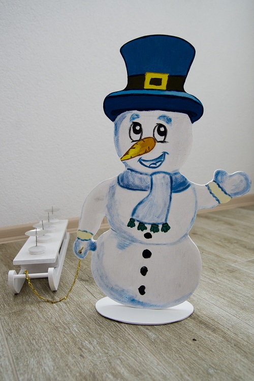 Dřevěný sněhulák se sáňky, jako adventní svícen.