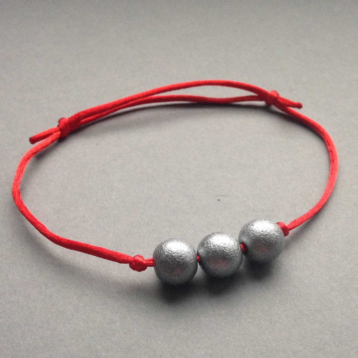 Červený náramek se třemi kuličkami
