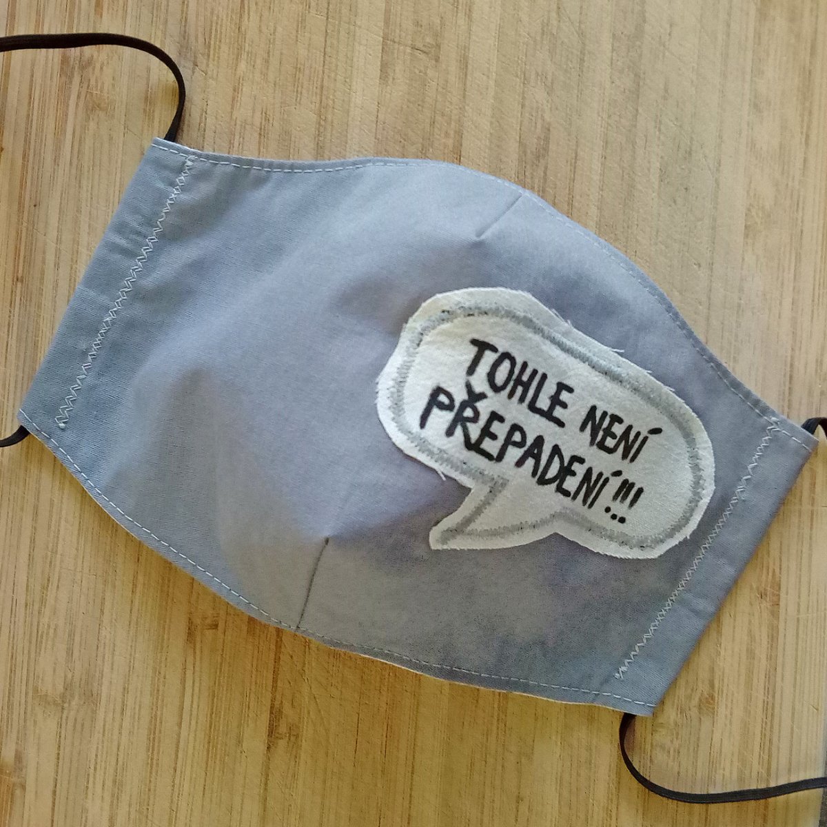 Šedá rouška s nápisem Tohle není přepadení!